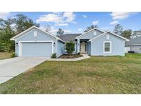 Charming one-story home with a well-manicured lawn, two car garage, and light blue painted siding at 15065 Se 93Rd Ave, Summerfield, FL 34491