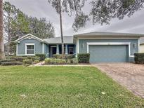 Charming single-story home with a well-manicured lawn, brick driveway, and a two-car garage at 163 Crepe Myrtle Dr, Groveland, FL 34736