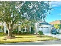 Single-story home with a two-car garage, mature landscaping, and golf cart at 2458 Dunkirk Trl, The Villages, FL 32162