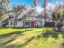 Charming ranch home with a red door, white exterior, and well-manicured lawn at 405 Mission Ln, Howey In The Hills, FL 34737