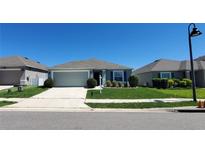 Charming single-story home with well-manicured lawn, blue shutters, and a two-car garage at 417 Pinecrest Loop, Davenport, FL 33837