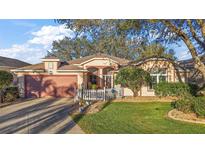 Charming single-story home with a well-manicured lawn, white picket fence, and attached two car garage at 4822 Sawgrass Lake Cir, Leesburg, FL 34748