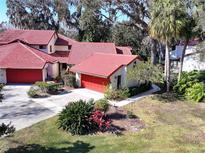 Aerial view of Spanish-style home with red tile roof and lush landscaping at 601 Waterwood Dr, Yalaha, FL 34797