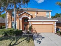 Two-story house with orange exterior, two-car garage, and landscaping at 804 Orange Cosmos Blvd, Davenport, FL 33837