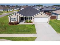 Tan house with gray roof, two-car garage, and well-manicured lawn at 11272 Stewart Loop, Oxford, FL 34484