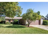 Ranch-style home with a spacious lawn, attached garage, and mature trees at 13635 Berkshire Ct, Grand Island, FL 32735