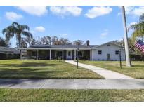 Brick ranch home with covered porch, mature landscaping, and walkway at 1401 Lake Shore Blvd, Tavares, FL 32778