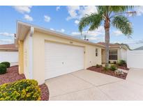 Attached garage with a white door and landscaping at 1521 Trenton Ln, The Villages, FL 32162