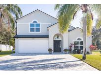 Two-story house with a gray exterior, white garage door, and landscaping at 17120 Cypresswood Way, Clermont, FL 34714