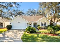 Cute yellow house with a 2-car garage and nicely landscaped lawn at 208 Desota Ct, The Villages, FL 32159