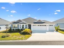 White two-car garage home with gray roof and landscaping at 2484 Lynette Ave, The Villages, FL 32163