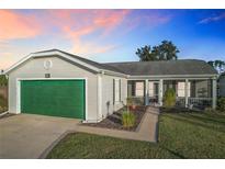 Single-story home with green garage door and screened porch at 25339 Hibiscus St, Leesburg, FL 34748