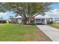 Single-story home with carport, mature landscaping, and large tree in front at 2753 Vindale Rd, Tavares, FL 32778