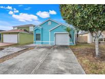 Cute teal house with a two-car garage and a small front yard at 500 Southern Charm Dr, Orlando, FL 32807