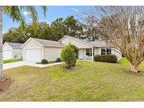 Tan house with garage and landscaped lawn at 860 Evelynton Loop, The Villages, FL 32162