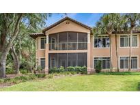 An impressive back exterior featuring a screened-in porch overlooking a well-maintained lawn and lush greenery at 102 Camino Real Blvd # 102, Howey In The Hills, FL 34737