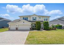 Charming two-story home featuring a three-car garage, lush landscaping, and blue shutters at 16428 Good Hearth Blvd, Clermont, FL 34711
