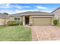 Curb appeal abounds in this charming single-story home, featuring a well-manicured lawn and paver driveway at 188 Williamson Dr, Davenport, FL 33897