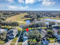 Aerial view of a house on a golf course community with a pond nearby at 26748 White Plains Way, Leesburg, FL 34748