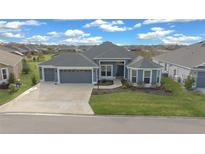 Gray two-story house with a three-car garage and landscaped yard at 4442 Shannon Loop, The Villages, FL 32163