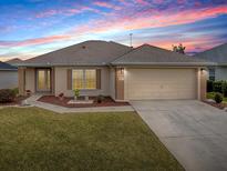 Well-maintained house with a landscaped lawn and a two-car garage at 8633 Se 133Rd Ln, Summerfield, FL 34491