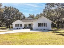 White farmhouse exterior with a large yard and concrete driveway at 871 Cr 548, Bushnell, FL 33513