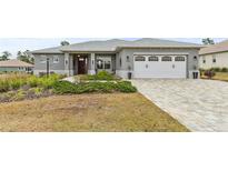 Gray house with white garage door, landscaped yard, and a paved driveway at 9287 Sw 102Nd Avenue Rd, Ocala, FL 34481