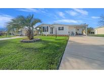 Landscaped lawn with palm tree and single-wide manufactured home at 1706 Pebble Beach Ln, Lady Lake, FL 32159