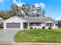 Charming single-story home featuring well-manicured lawn, a screened garage, and tidy landscaping at 25941 Newcombe Cir, Leesburg, FL 34748