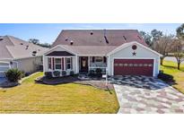 Single-story home with a red door and patterned driveway at 2762 Morven Park Way, The Villages, FL 32162