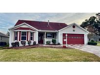 One-story home with red roof, red garage door, and landscaped lawn at 2762 Morven Park Way, The Villages, FL 32162