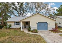 Cute yellow house with blue garage door, landscaped lawn, and walkway at 312 Brigadoon Cir # 312, Leesburg, FL 34788