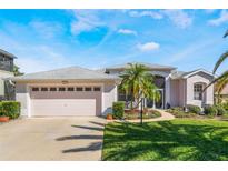 Charming single-story home with a two-car garage and a beautifully landscaped front yard with tropical plants at 5502 Bounty Cir, Tavares, FL 32778