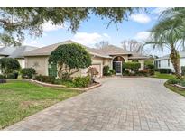 Single story home with paver driveway and manicured landscaping at 6216 Landings Blvd, Lady Lake, FL 32159