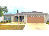 Tan one-story house with green shutters, attached garage, and landscaped yard at 9616 Se 168Th Elderberry Pl, The Villages, FL 32162