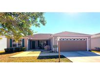 One-story home with a beige exterior, two-car garage, and landscaped yard at 9616 Se 168Th Elderberry Pl, The Villages, FL 32162