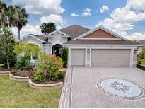 Two-story house with a three-car garage and landscaped front yard at 5911 Delphina Loop, The Villages, FL 32163