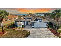 Stunning curb appeal: Two-story home with lake view, gray exterior, and paver driveway at 10173 Lake Miona Way, Oxford, FL 34484