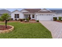 White house with landscaped yard, paver driveway, and two-car garage at 1216 Addison Ave, The Villages, FL 32162