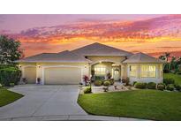 Charming single-Gathering home boasts a spacious three-car garage, meticulously landscaped yard, and a welcoming facade at sunset at 1276 Bennett Pl, The Villages, FL 32162