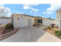 Light yellow house with white garage door, landscaped yard, and walkway at 1410 Conchas Dr, The Villages, FL 32162