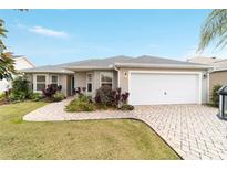 House exterior showcasing a two-car garage and a neatly landscaped front at 1548 Loris Loop, The Villages, FL 32162