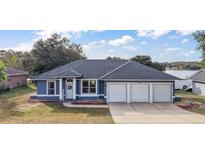 Beautiful blue house with a three-car garage and well-manicured lawn at 16029 Worthington N Blvd, Mascotte, FL 34753