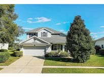 Two-story house with a gray roof, white garage door, and lush landscaping at 3898 Beacon Ridge Way, Clermont, FL 34711