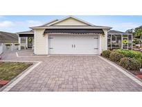 Attached garage with black awning over paved driveway at 392 Arbella Loop, The Villages, FL 32162