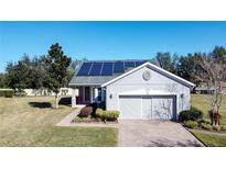 Charming home with a well-manicured lawn, brick driveway, and solar panels on the roof at 409 Silver Maple Rd, Groveland, FL 34736