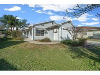 Charming single-story home featuring light blue siding, an attached garage, and a well-maintained lawn at 7 Ginger Cir, Leesburg, FL 34748