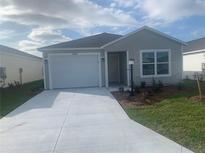 Newly constructed home with a white garage door and landscaping at 7268 Annison Ter, The Villages, FL 32163