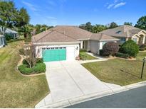 Single-story home with green garage door, landscaping, and paved driveway at 9397 Se 124Th Pl, Summerfield, FL 34491