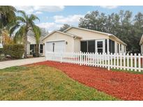 Tan house with white picket fence, landscaped yard, and two-car garage at 17461 Se 93Rd Retford Ter, The Villages, FL 32162